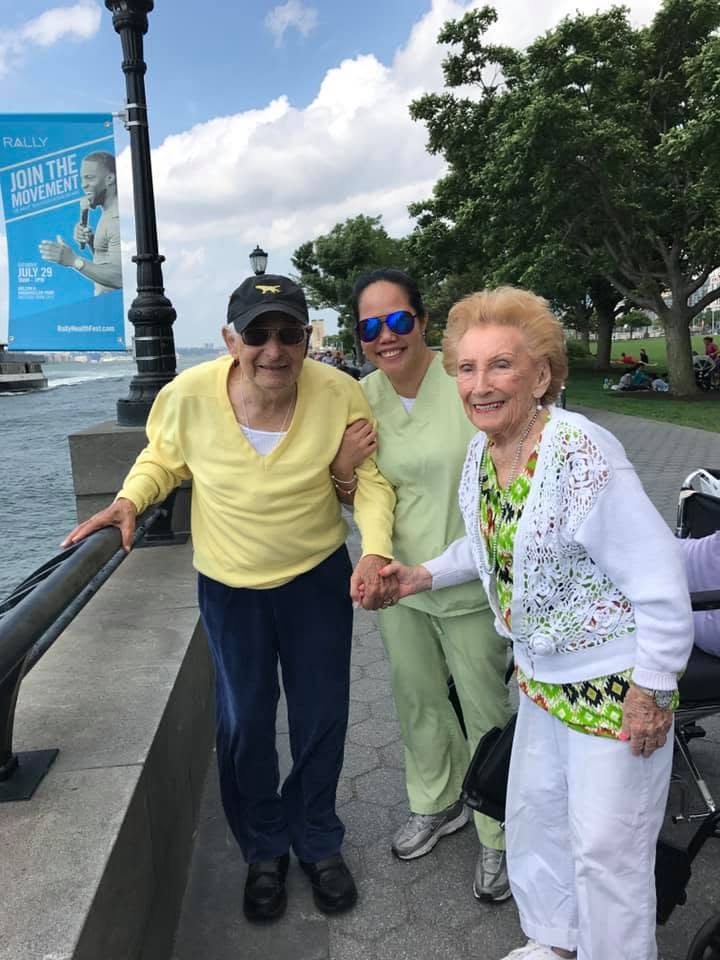 A caregiver walking two clients along a waterfront path