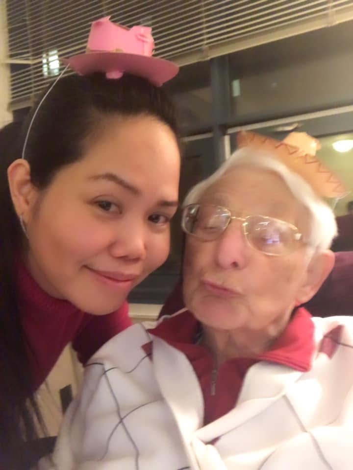 A caregiver and a client in party hats, laughing together
