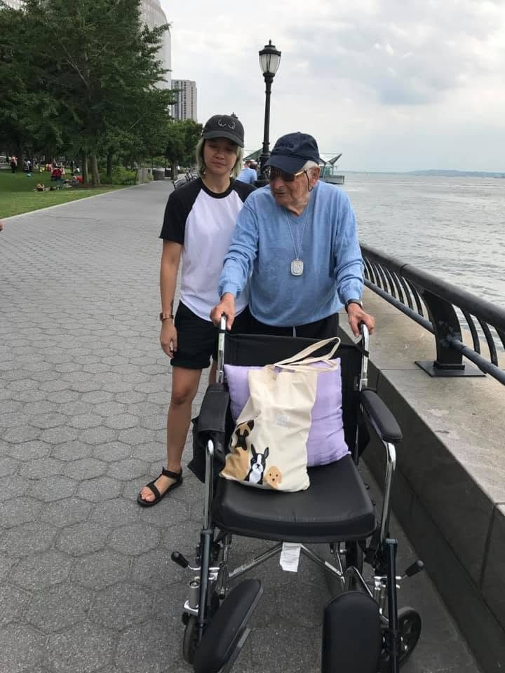 A caregiver steadying a client with a rollator on a waterfront path